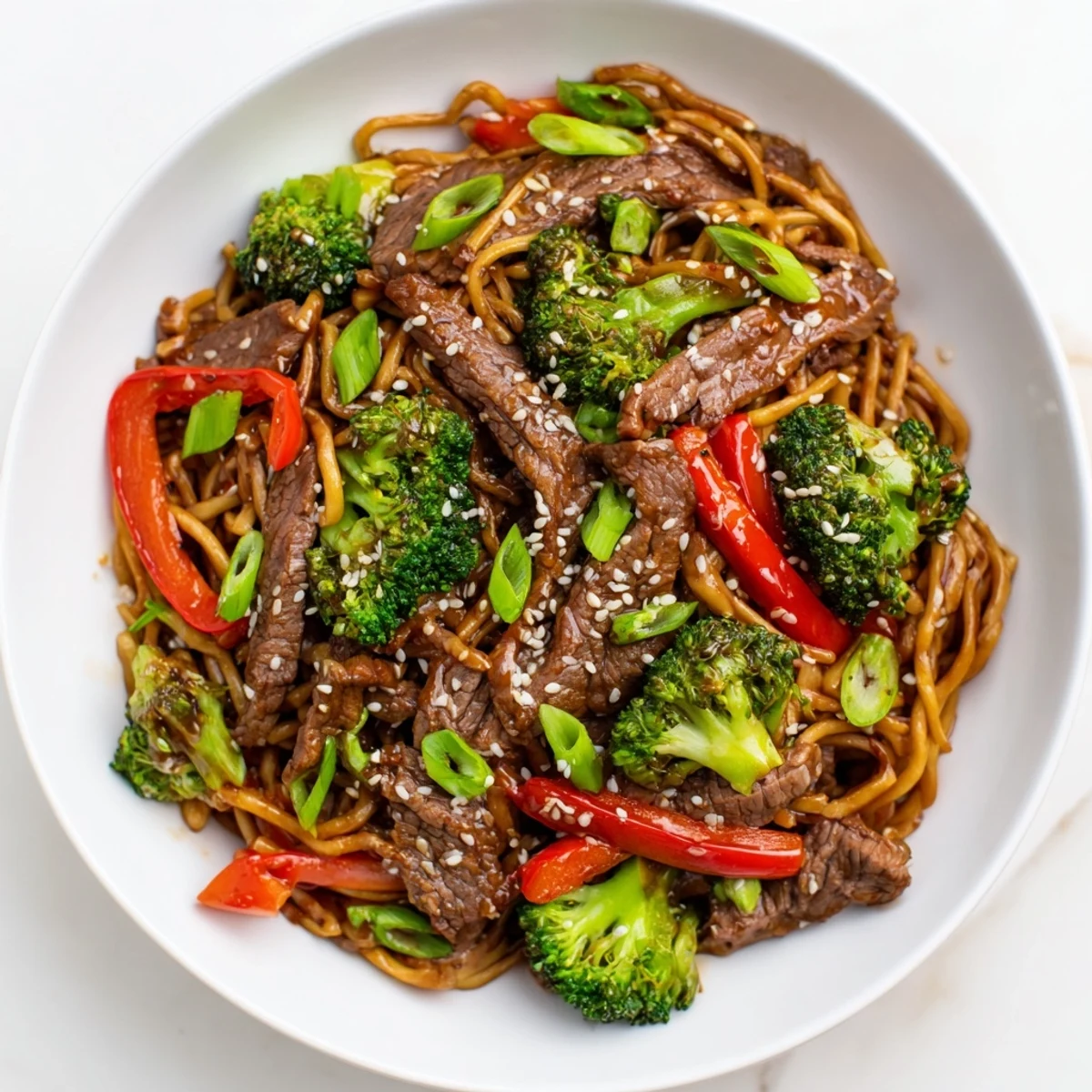 A close-up of delicious Beef and Broccoli Lo Mein, sprinkled with sesame seeds, presented in a wok.