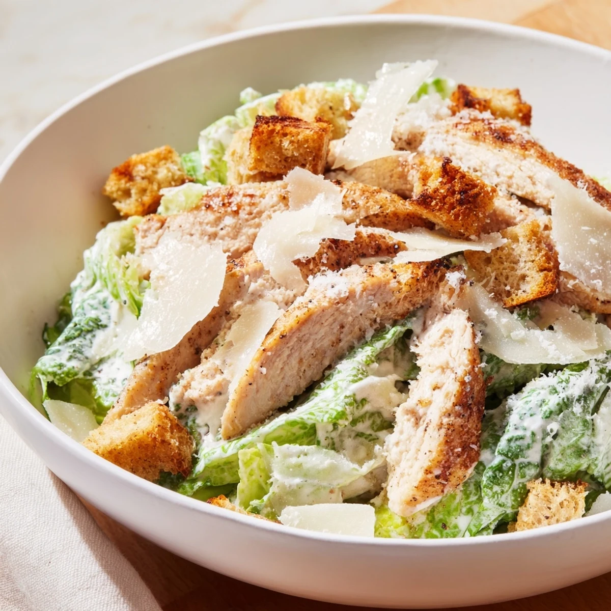 Topped with crunchy croutons, shaved Parmesan, and creamy Caesar dressing in a large bowl.
