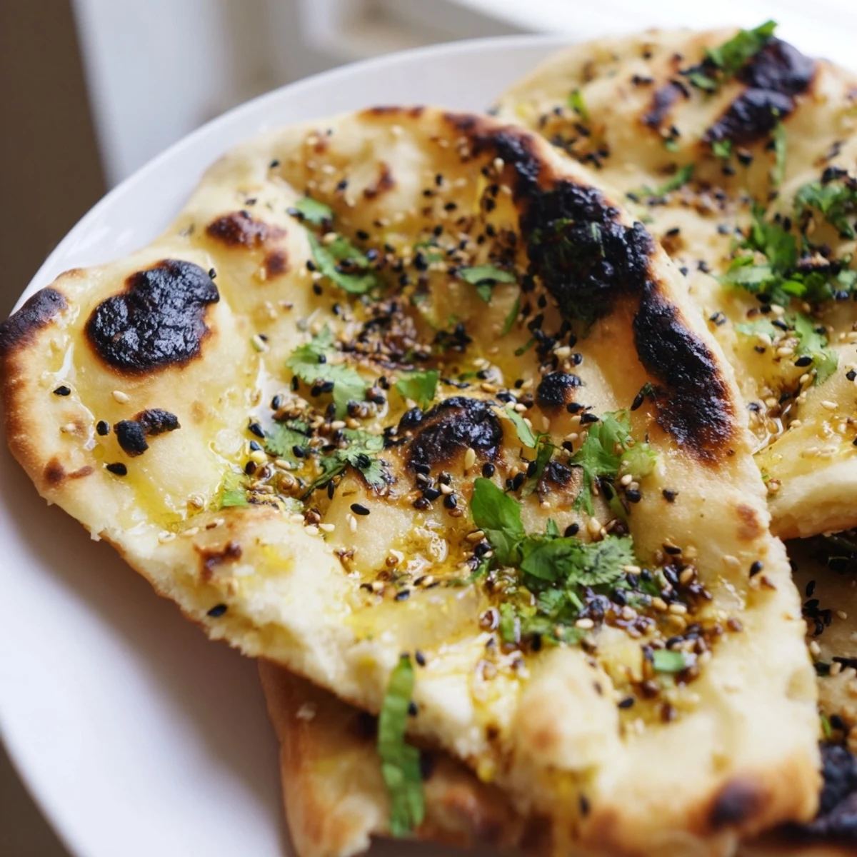 Fluffy Garlic Naan Bread with Nigella Seeds served warm alongside a bowl of spicy curry.