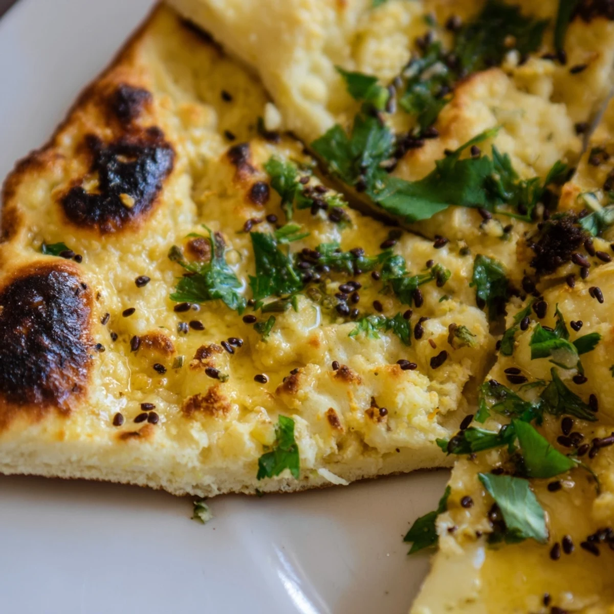 Golden toasted Garlic Naan Bread with Nigella Seeds topped with fresh cilantro and minced garlic.