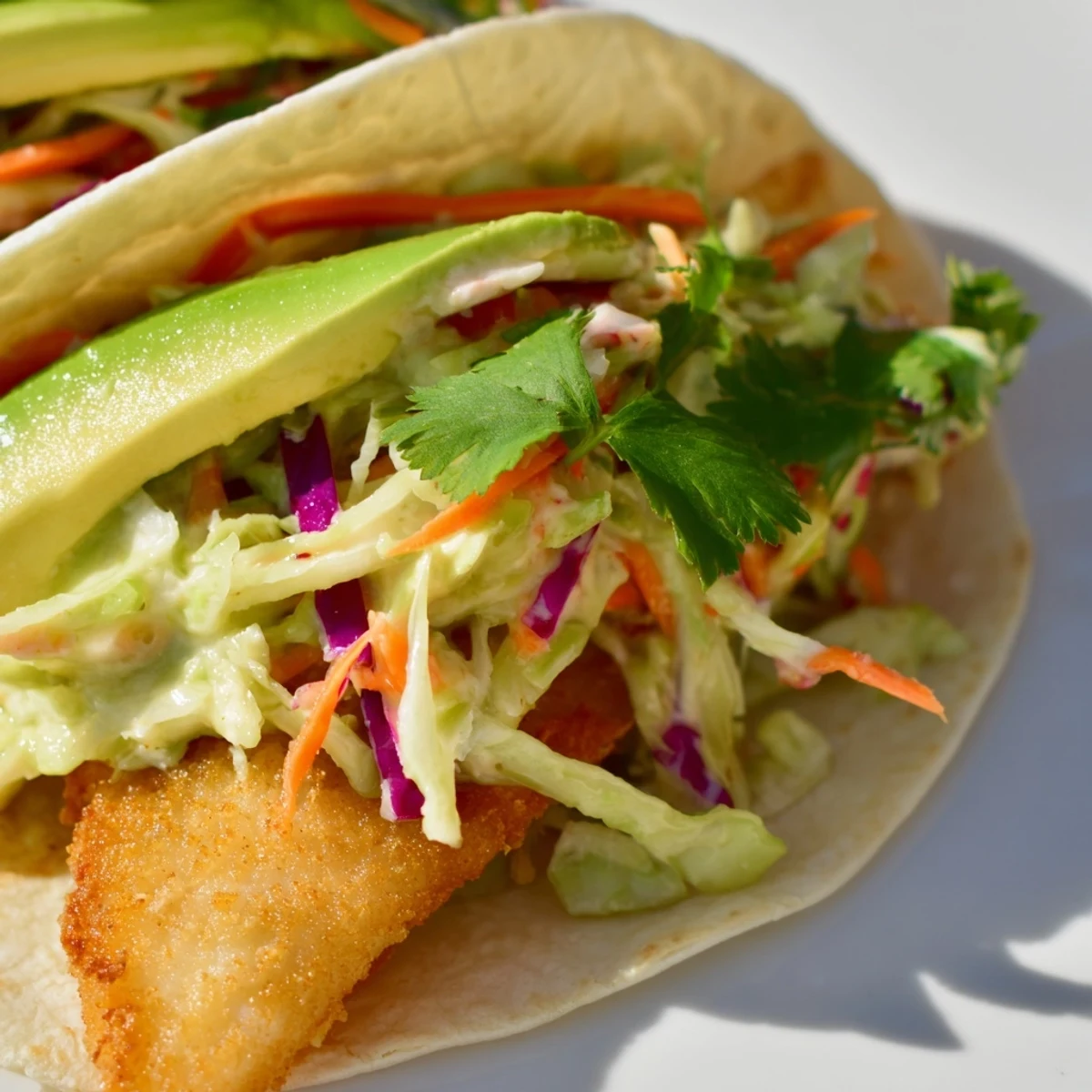 Mouthwatering fish tacos featuring golden fried cod strips, shredded purple cabbage slaw, and fresh lime garnish on a wooden cutting board.
