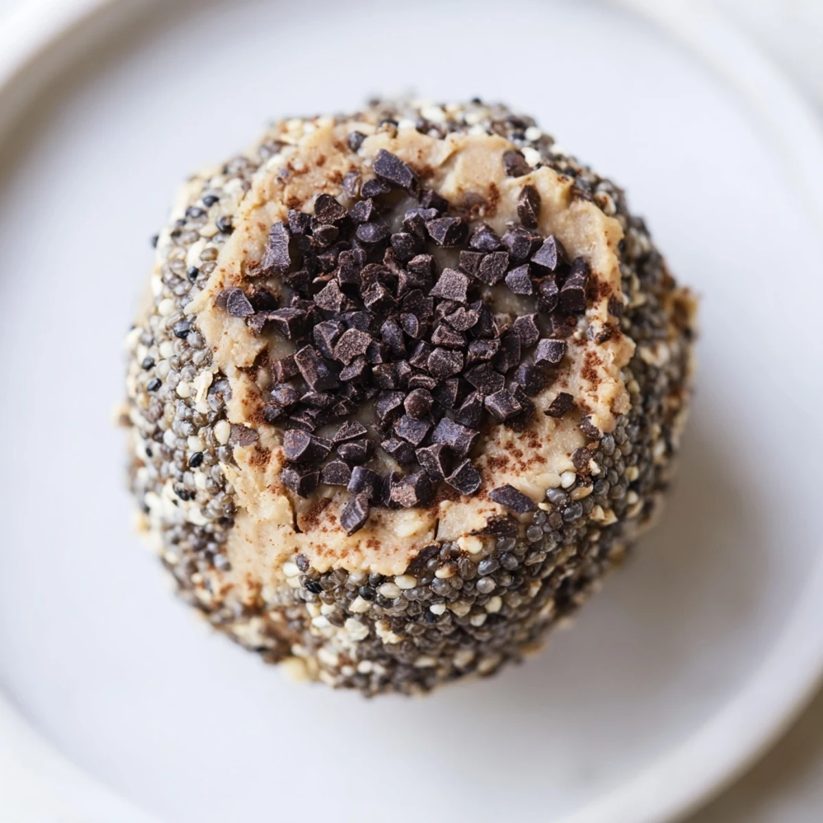 Close-up of glossy Chocolate Peanut Butter Energy Balls coated in shredded coconut, with oats and mini chocolate chips visible. 