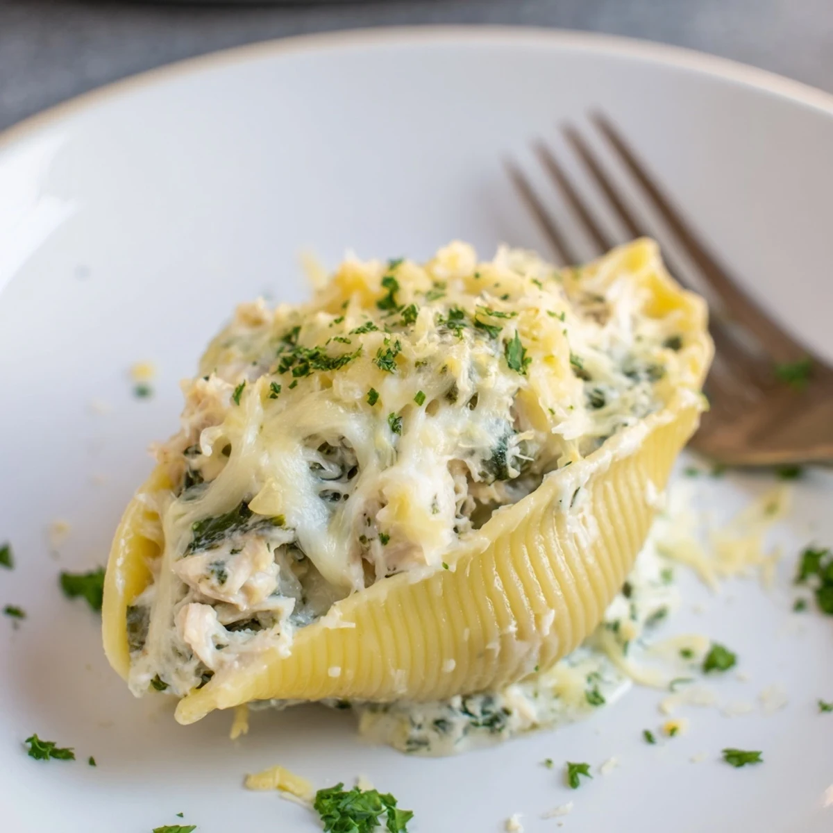 Golden-brown baked Chicken Alfredo Stuffed Shells with Spinach bubbling with cheesy goodness in a white dish.