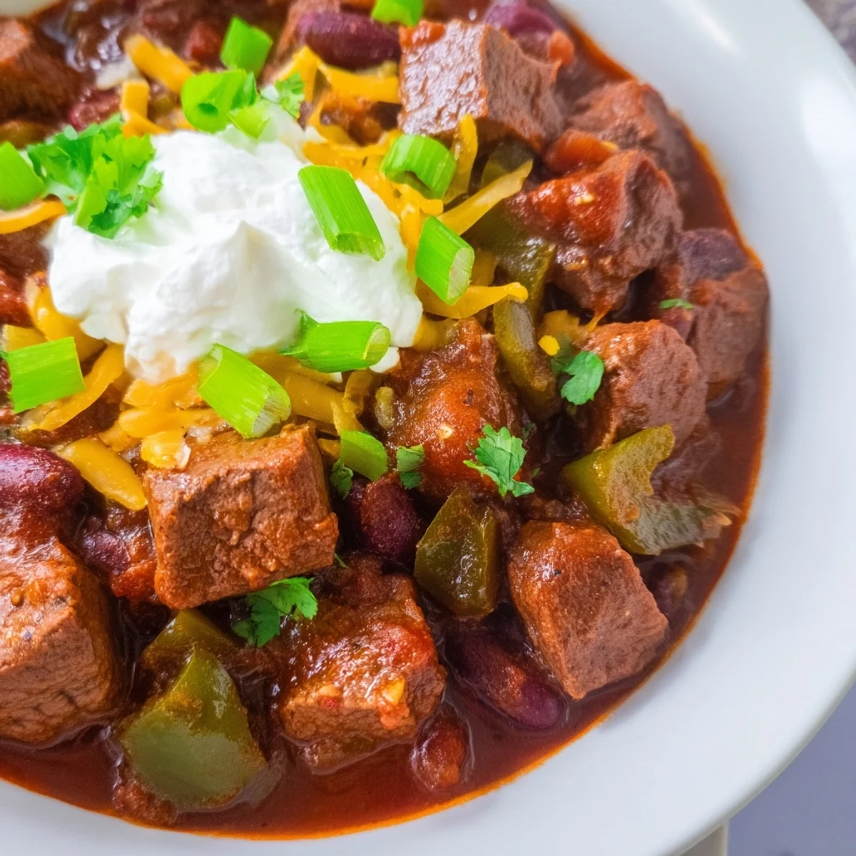 Slow Cooker Beef Chili with Kidney Beans and Tomato served hot, topped with sour cream and sliced green onions for a cozy meal.
