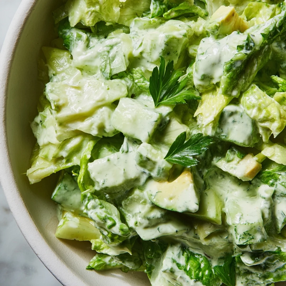 The Green Goddess Salad in a glass bowl with fresh parsley, basil, and crunchy romaine, served as a refreshing vegetarian lunch.