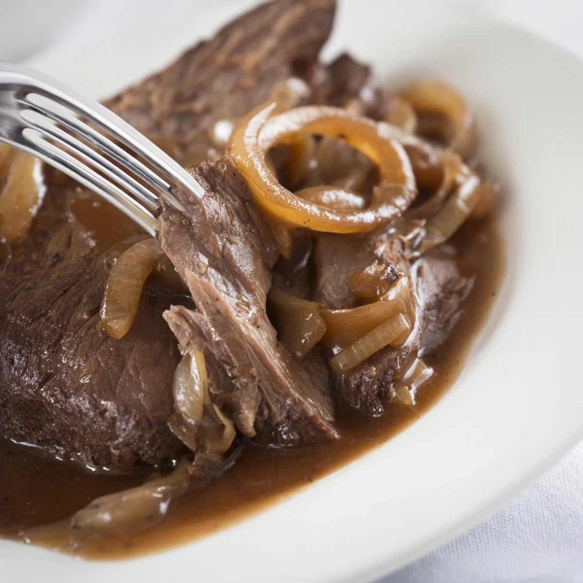 A plated serving of slow cooker pot roast, rich gravy, and vegetables ready to enjoy.