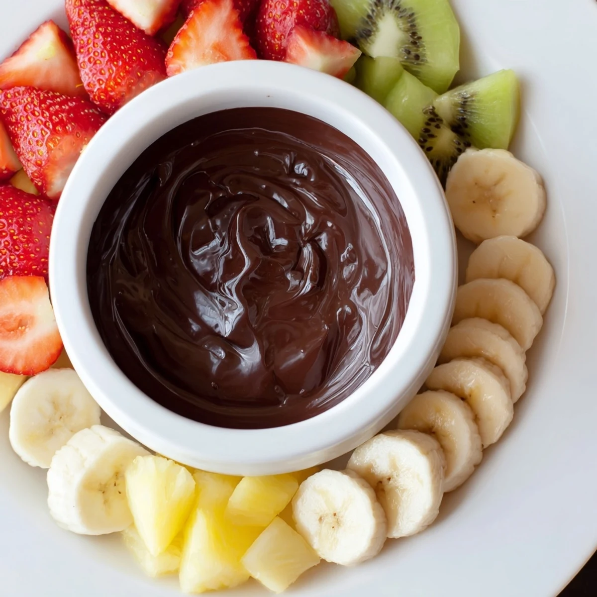 Steaming Romantic Chocolate Fondue with Fruit Platter cascades from a fondue pot onto fresh strawberries and pineapple chunks.