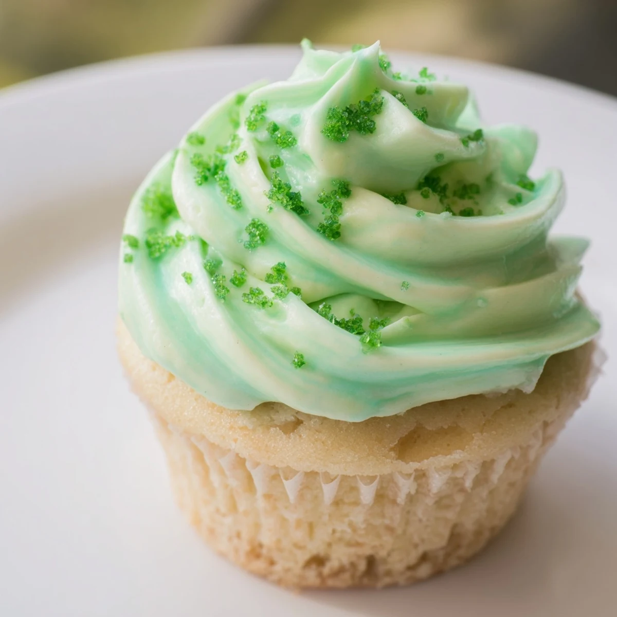 A close-up of a Shamrock Shake Cupcake with mint frosting, showing moist crumb and piped swirls for St. Patrick's Day dessert.  