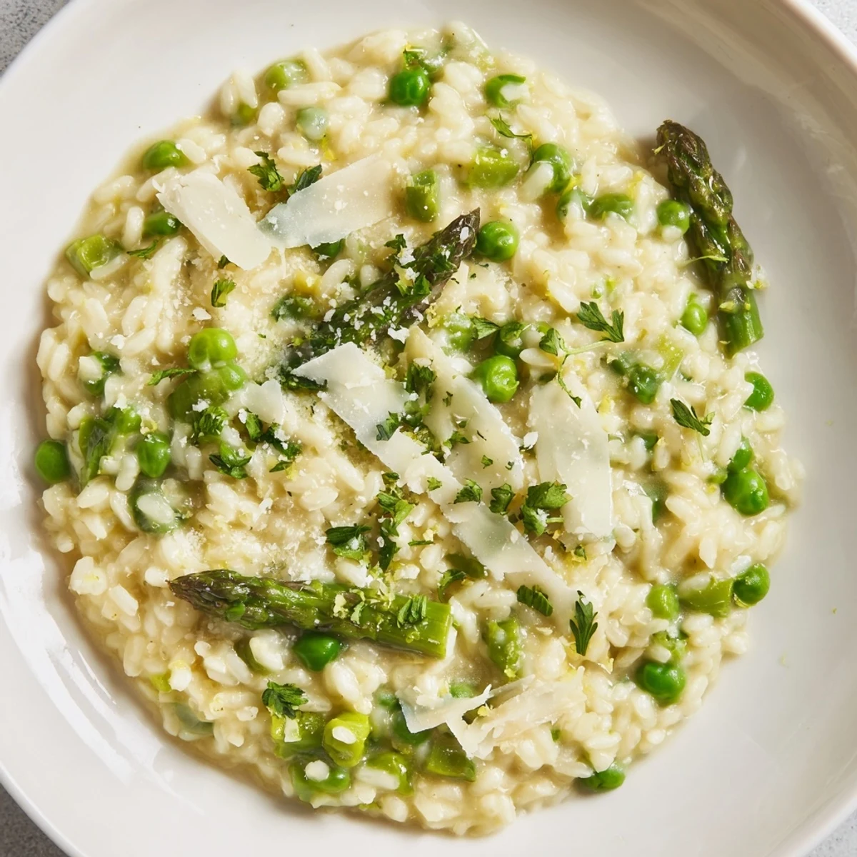 Spring Pea and Asparagus Risotto garnished with parsley and lemon zest in a rustic bowl.