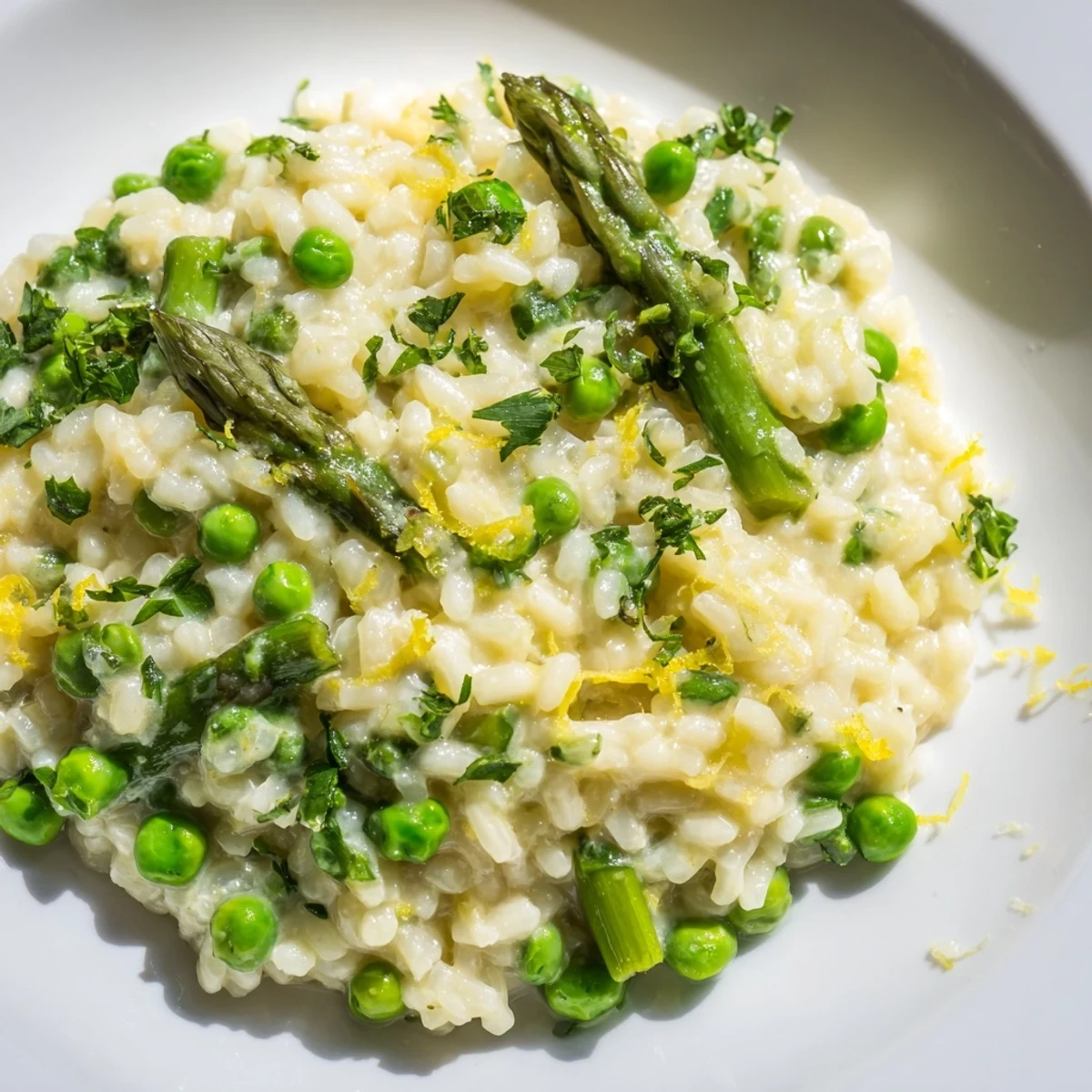 Spring Pea and Asparagus Risotto with tender green vegetables on a warm dinner plate next to white wine.