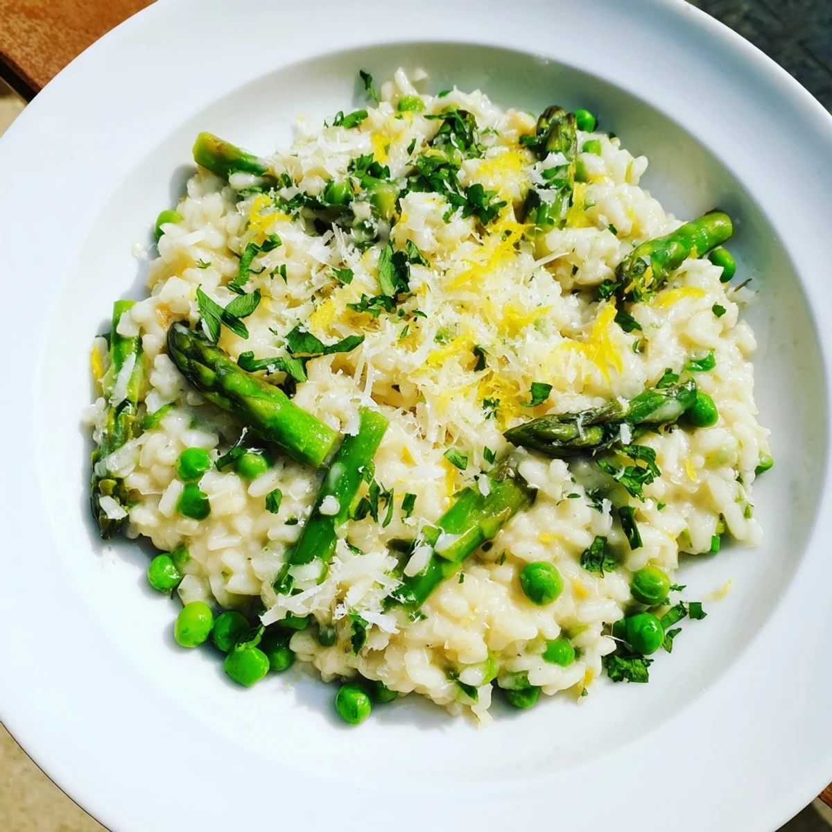 A close-up of Spring Pea and Asparagus Risotto, garnished with fresh parsley and lemon zest for bright flavor.