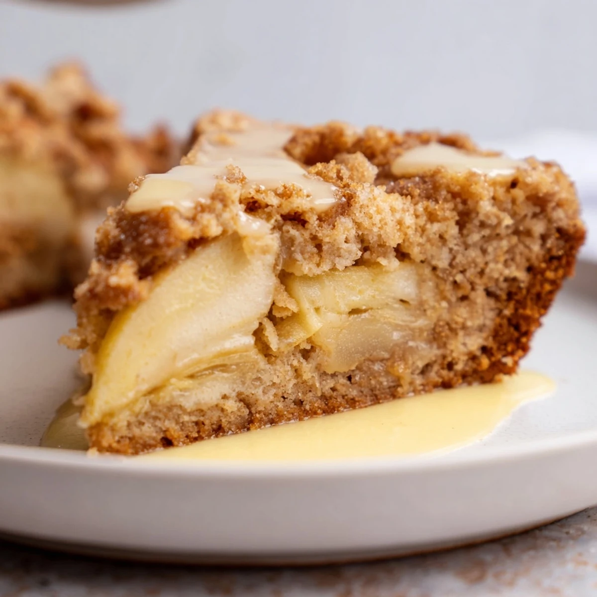 Close-up of a slice of Irish Apple Cake with Custard, revealing moist, tender cake studded with tart apple pieces and a hint of spice.