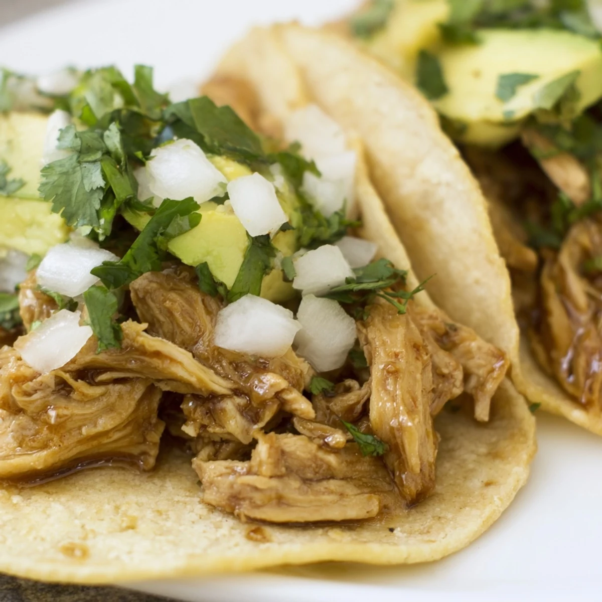Sizzling marinated chicken rests in warm corn tortillas for Chicken Street Tacos, garnished with fresh cilantro and diced onion.