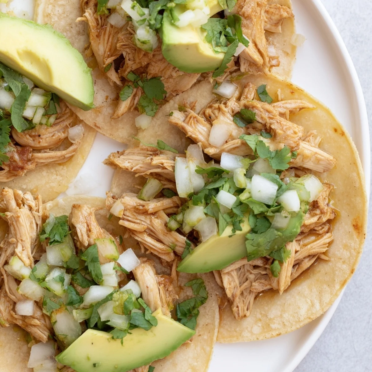Juicy grilled chicken thighs fill soft corn tortillas for Chicken Street Tacos, topped with creamy avocado and crumbled cotija cheese.