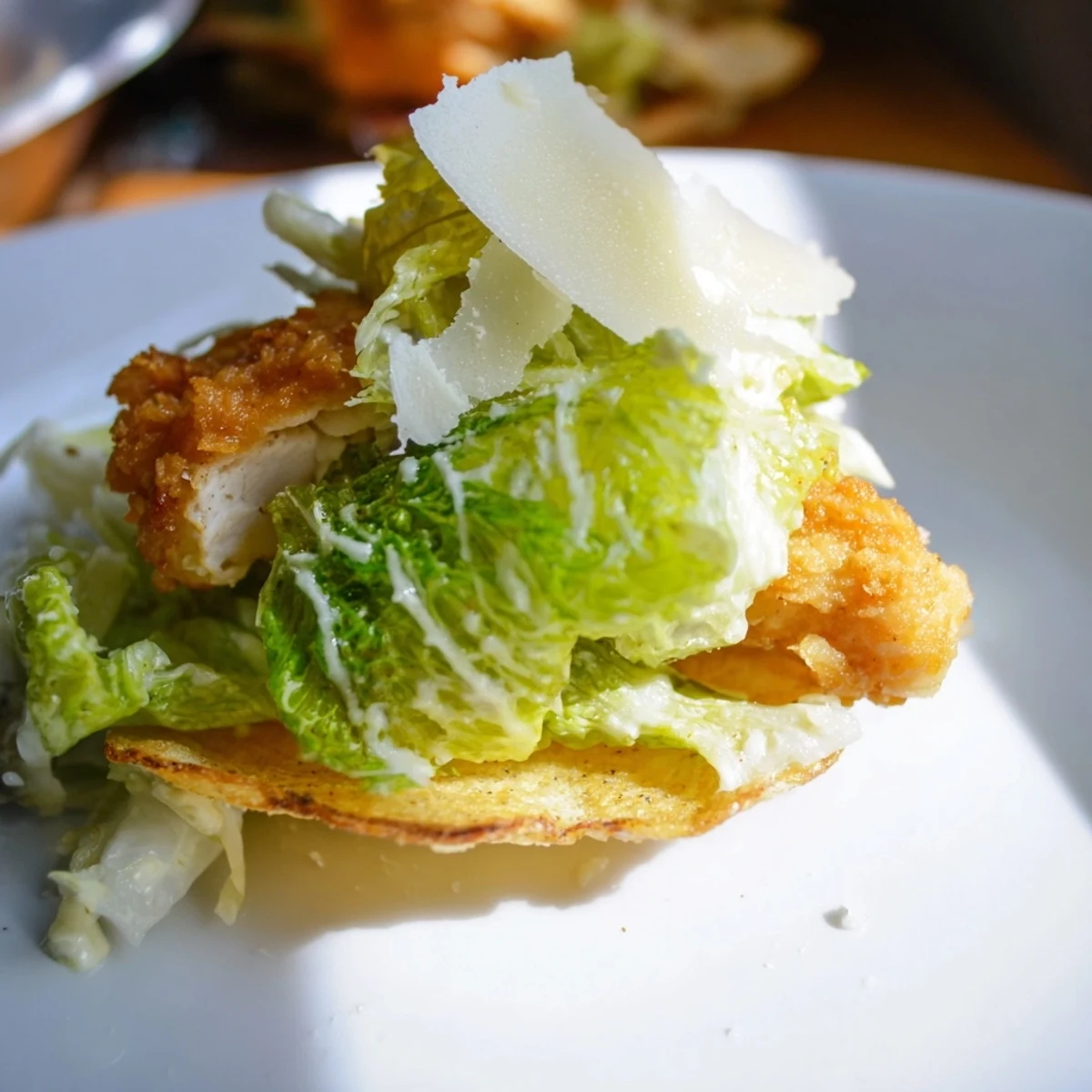 A close-up shows Crispy Chicken Caesar Salad Chips served with lemon wedges on a rustic wooden board for sharing.