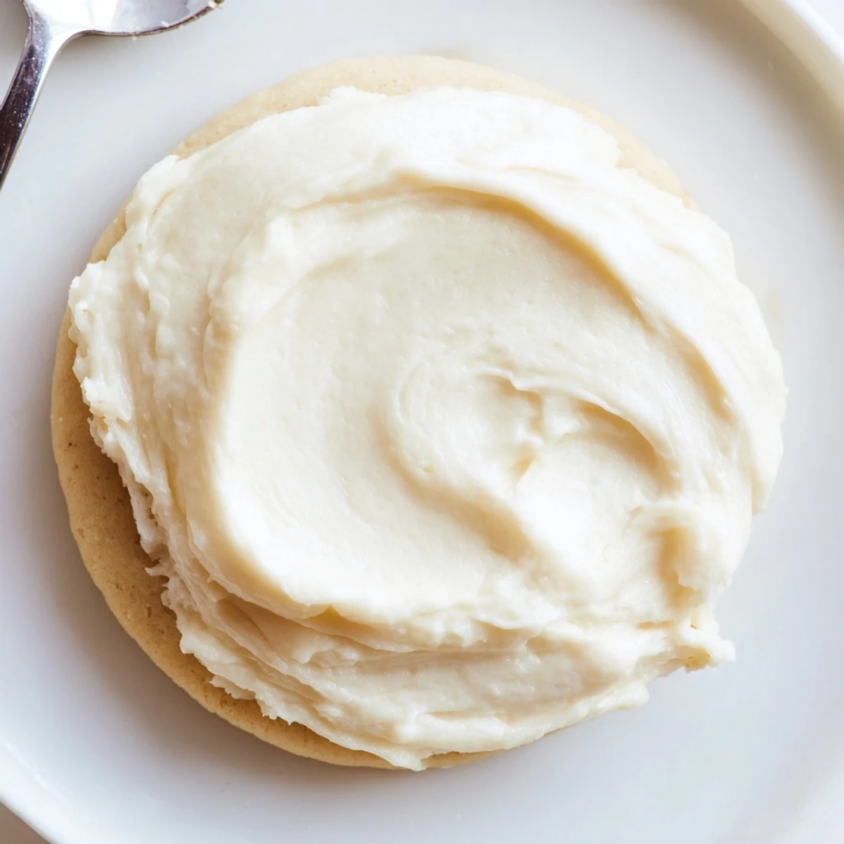 A bowl of creamy Easy Sugar Cookie Frosting with fluffy vanilla buttercream and a slight crust, ready to spread.