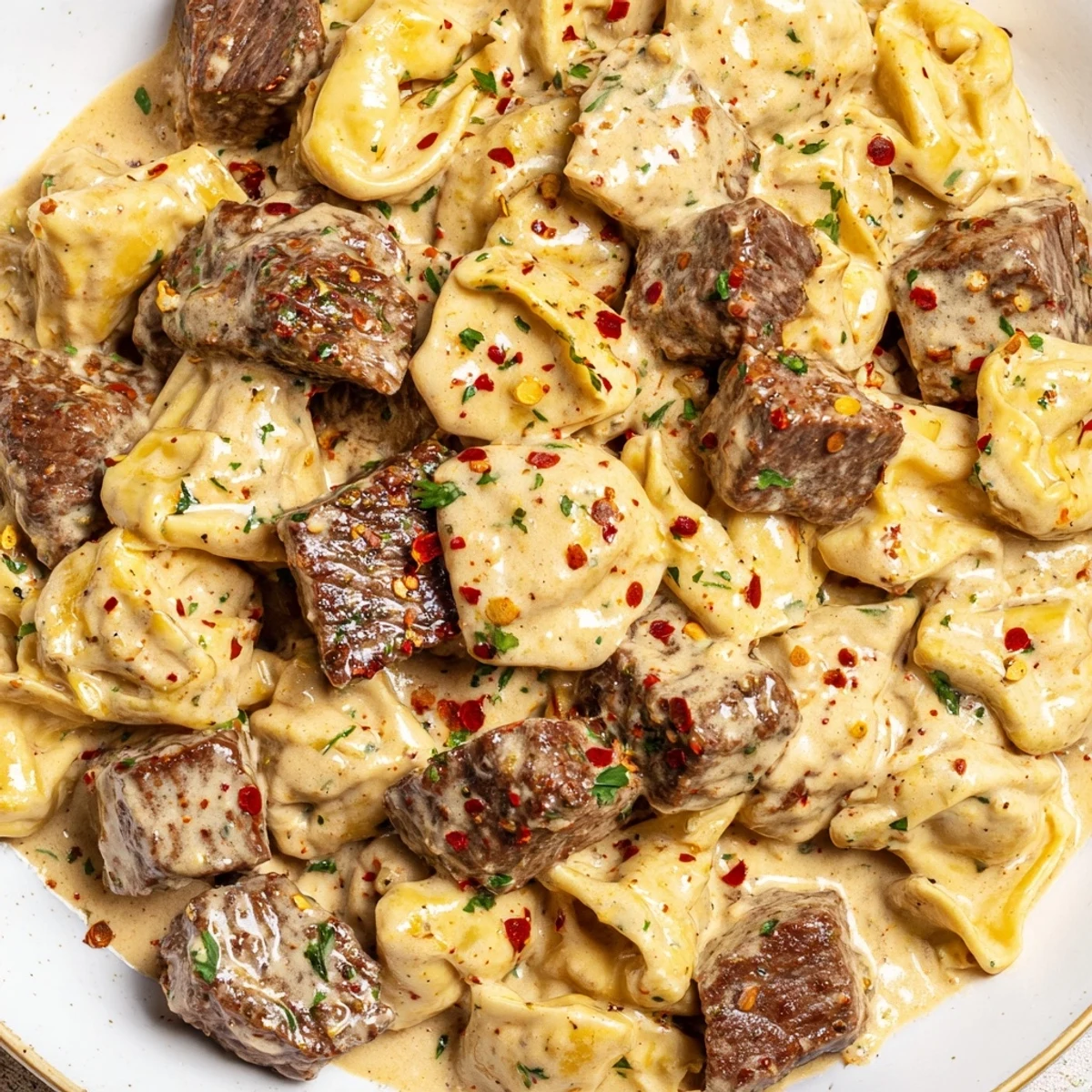 Sizzling Garlic Steak Tortellini served family-style in a skillet, topped with melted parmesan and garlic butter.