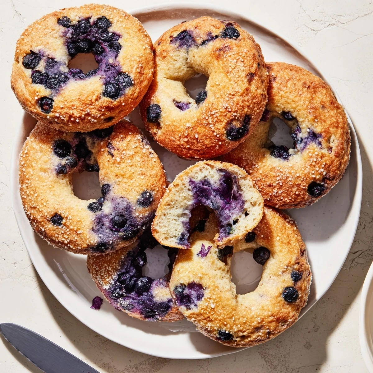 Homemade Gluten-Free Blueberry Bagels served on a plate with honey and a cup of coffee.