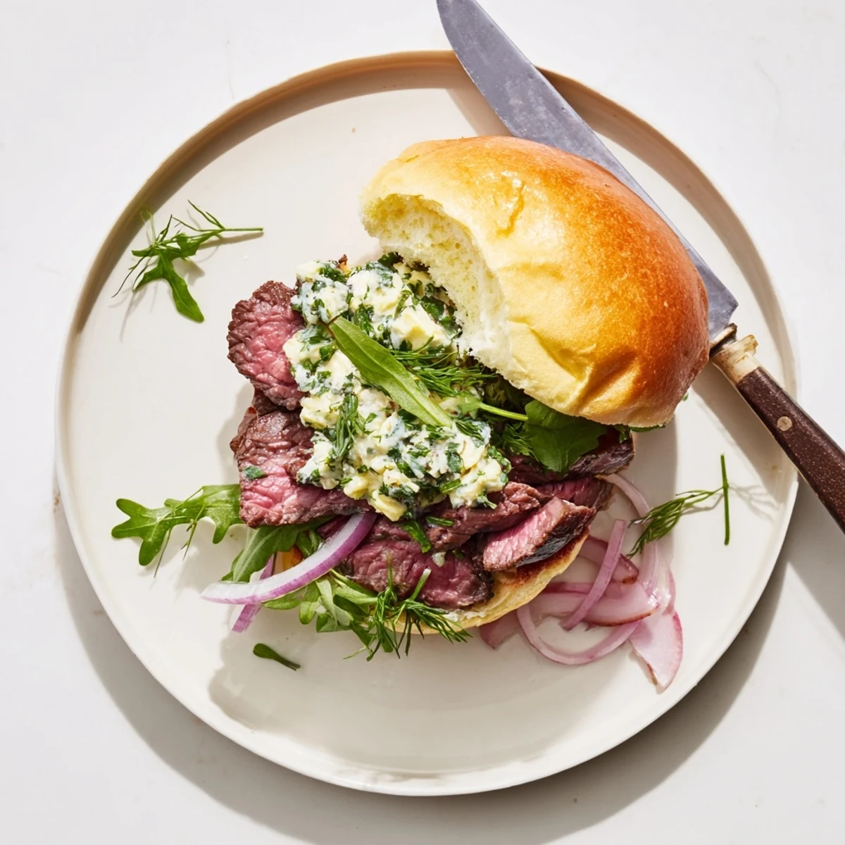 Freshly assembled Cowboy Butter Steak Sliders stacked high with spicy butter sauce, red onion, and bright arugula leaves.
