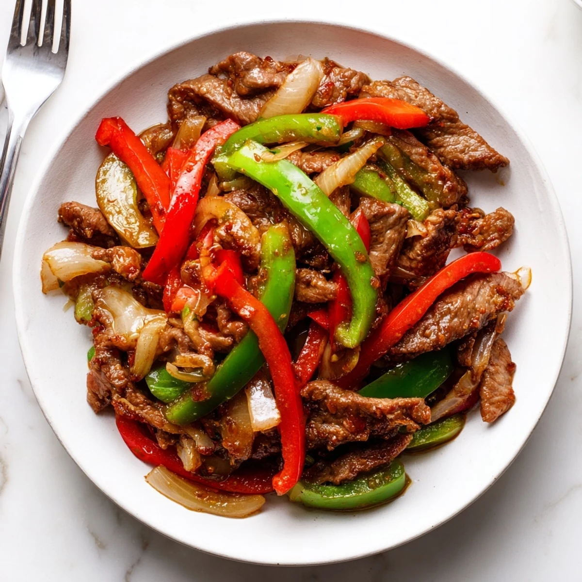 Glossy, savory Sizzling Chinese Pepper Steak With Onions plated with bright bell peppers and onions for a weeknight meal.