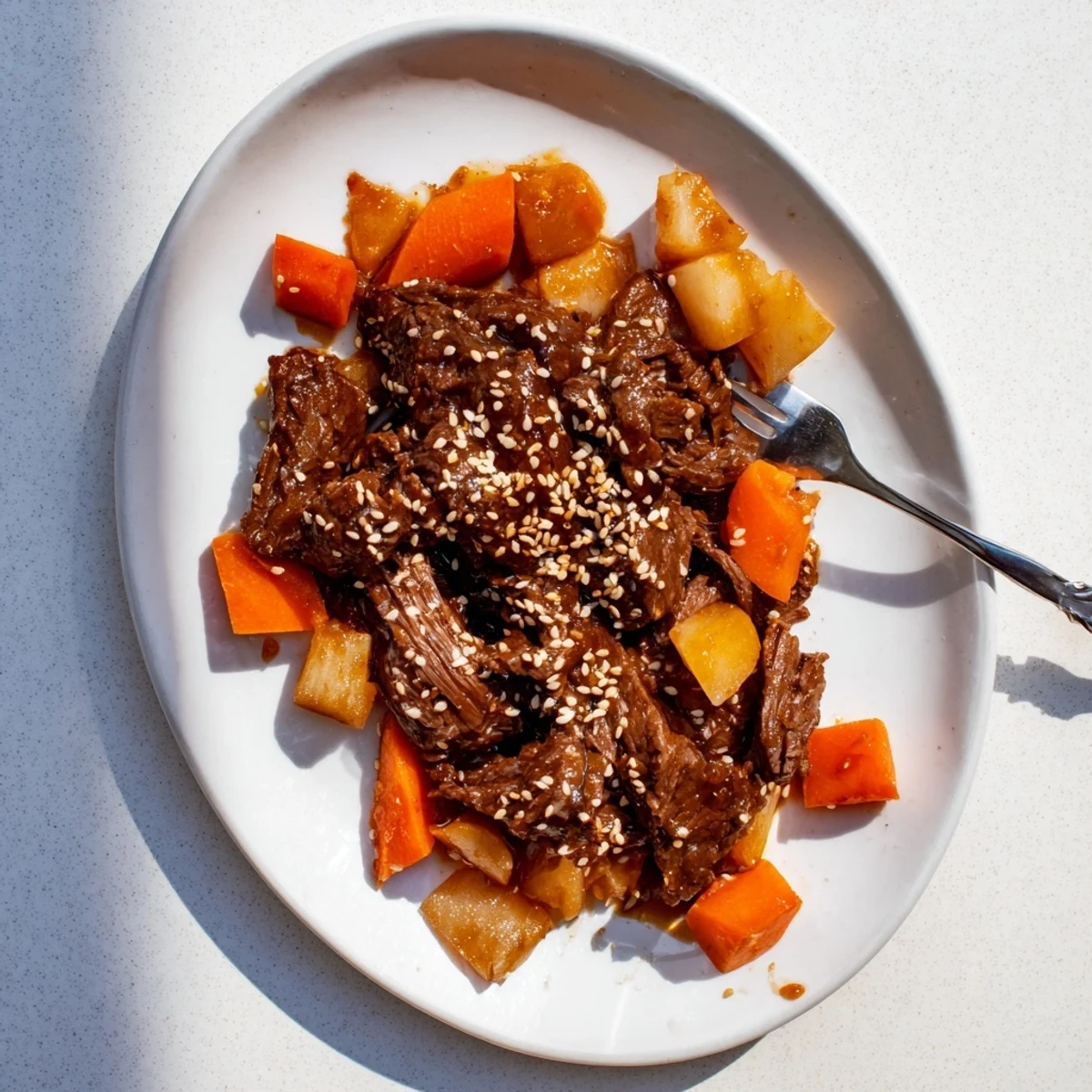 Korean Style Pot Roast glazed in a rich, dark sauce with scallions and sesame seeds garnish.