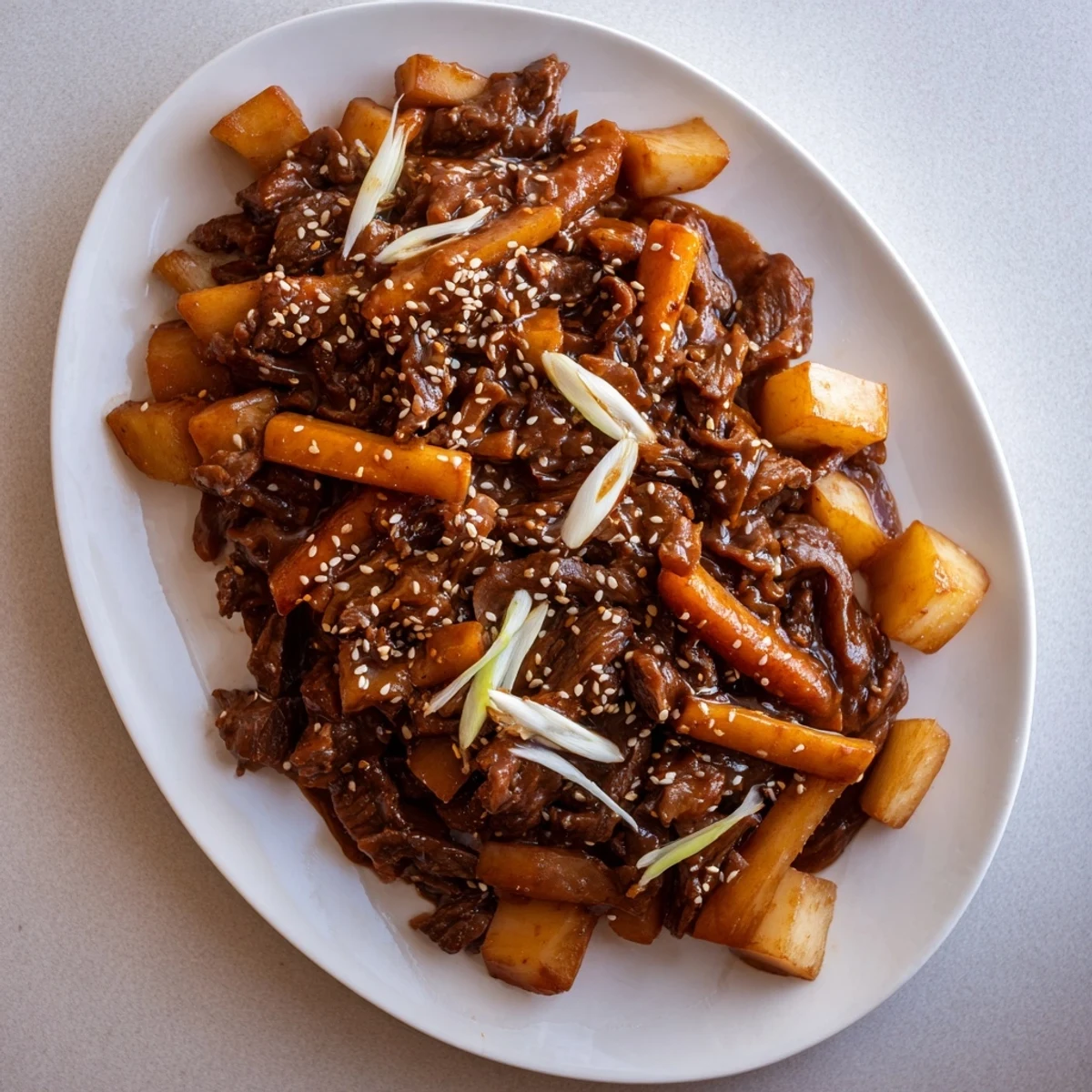 Serving spoon lifting shredded Korean Style Pot Roast over steamed rice with daikon and onions nearby.