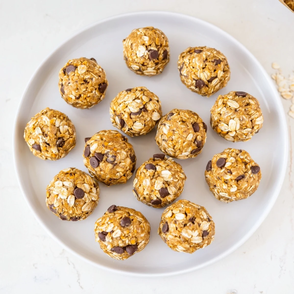 Freshly rolled No Bake Peanut Butter Energy Bites arranged on a chilled tray, showcasing their chewy texture and mini chocolate chips.