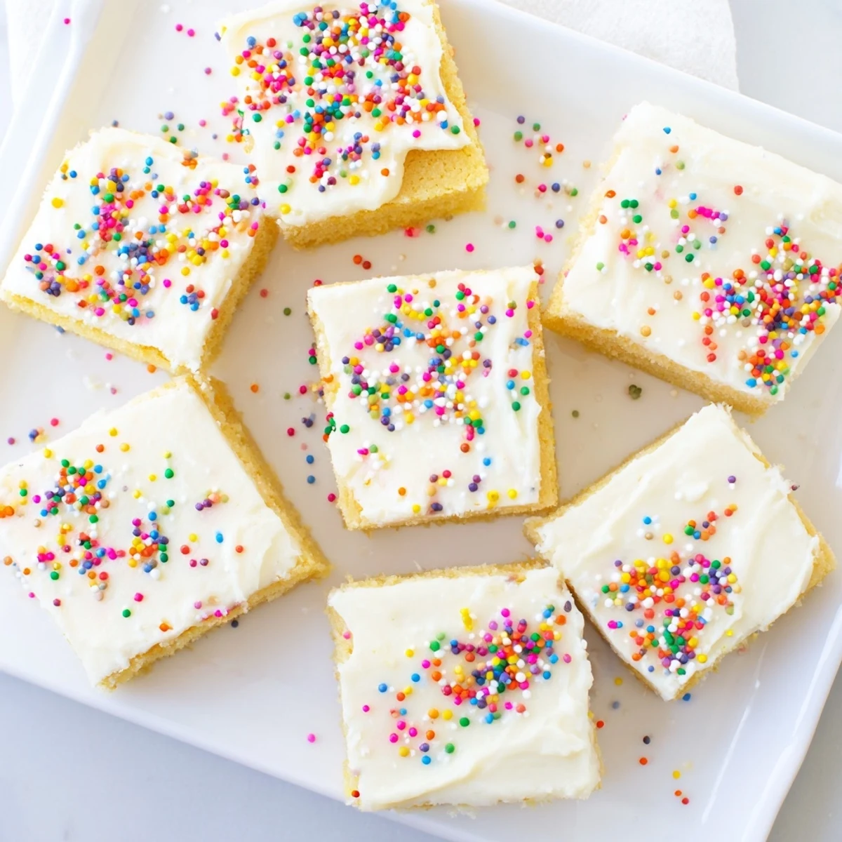 Homemade sugar cookie bars spread with smooth buttercream frosting and garnished with bright party sprinkles for dessert