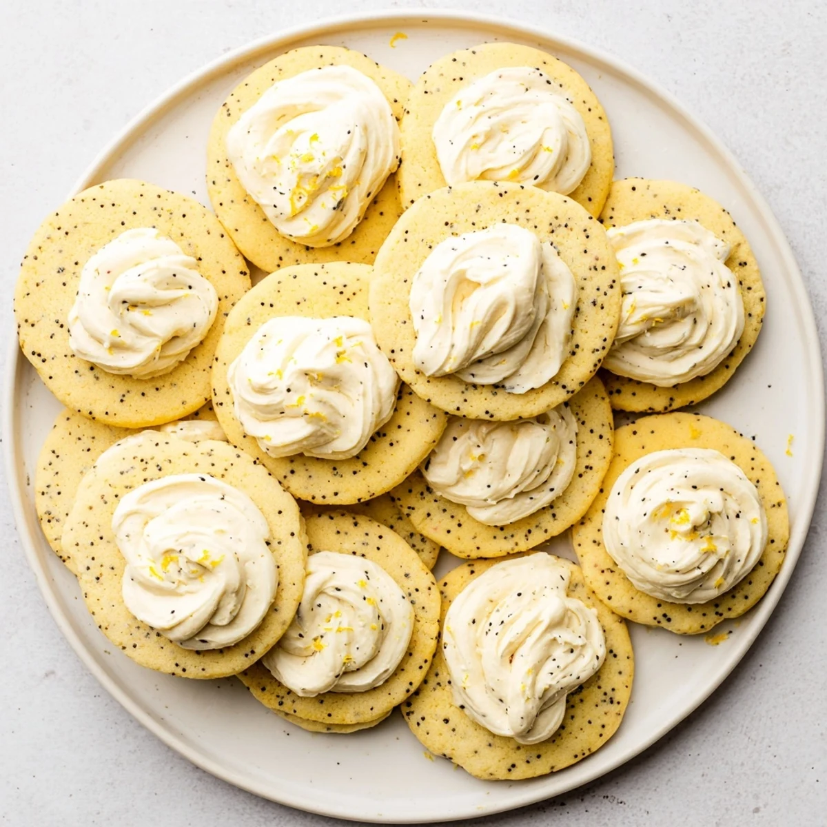 Buttery lemon poppy seed cookies speckled with seeds and covered in tangy cheesecake frosting