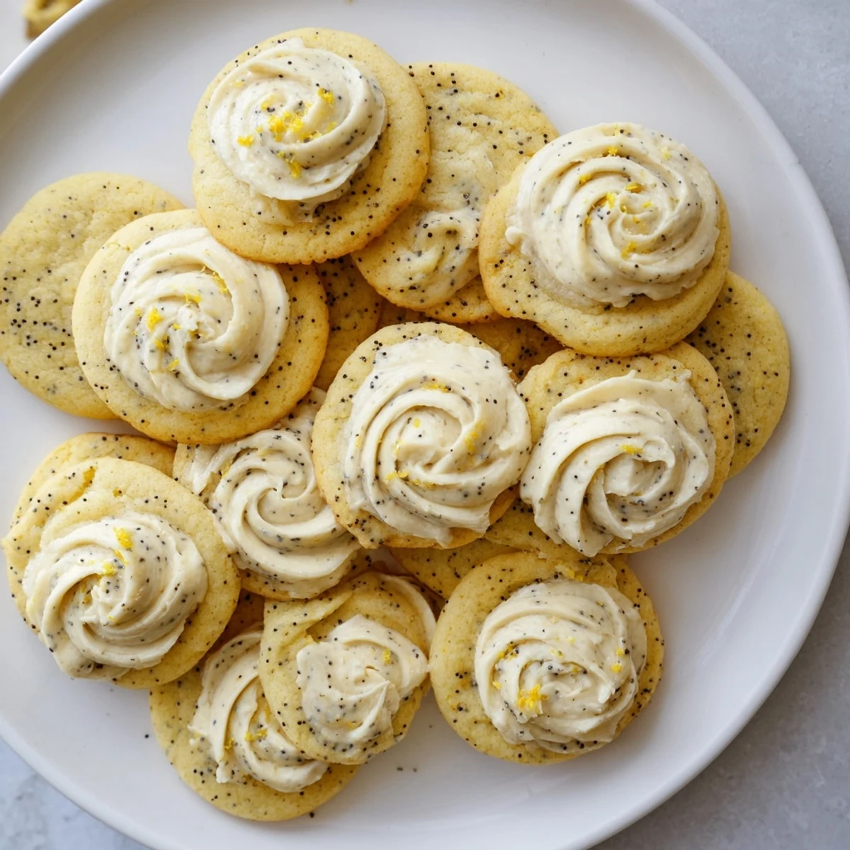 Stack of lemon poppy seed cookies with thick cheesecake frosting and lemon zest garnish
