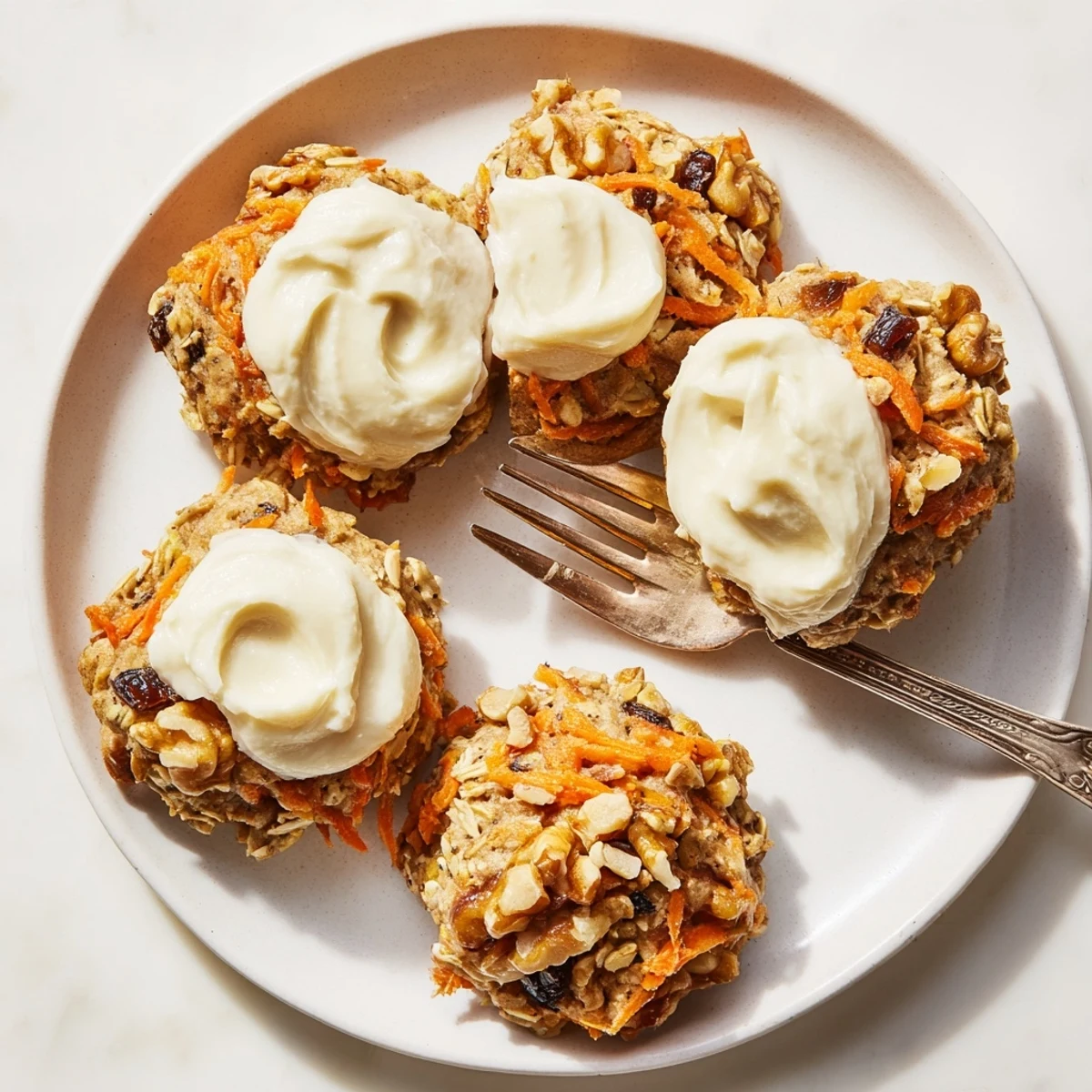 Soft carrot cake cookies topped with creamy white frosting and sprinkled with chopped walnuts