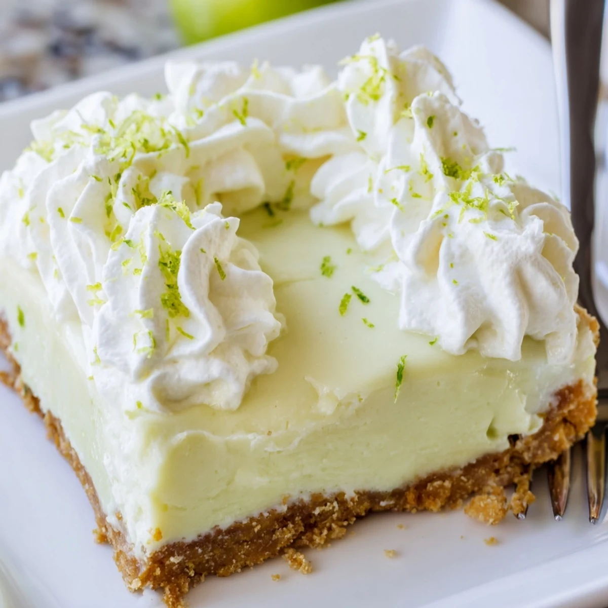 Fresh Key Lime Pie Bars cut into neat squares on white plate showing pale green filling and buttery base