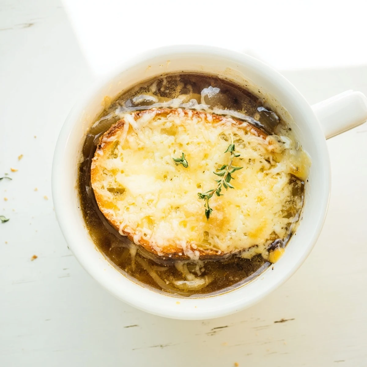 Oven-safe bowl of classic French onion soup topped with golden bread slice and generously grated cheese broiled until bubbling