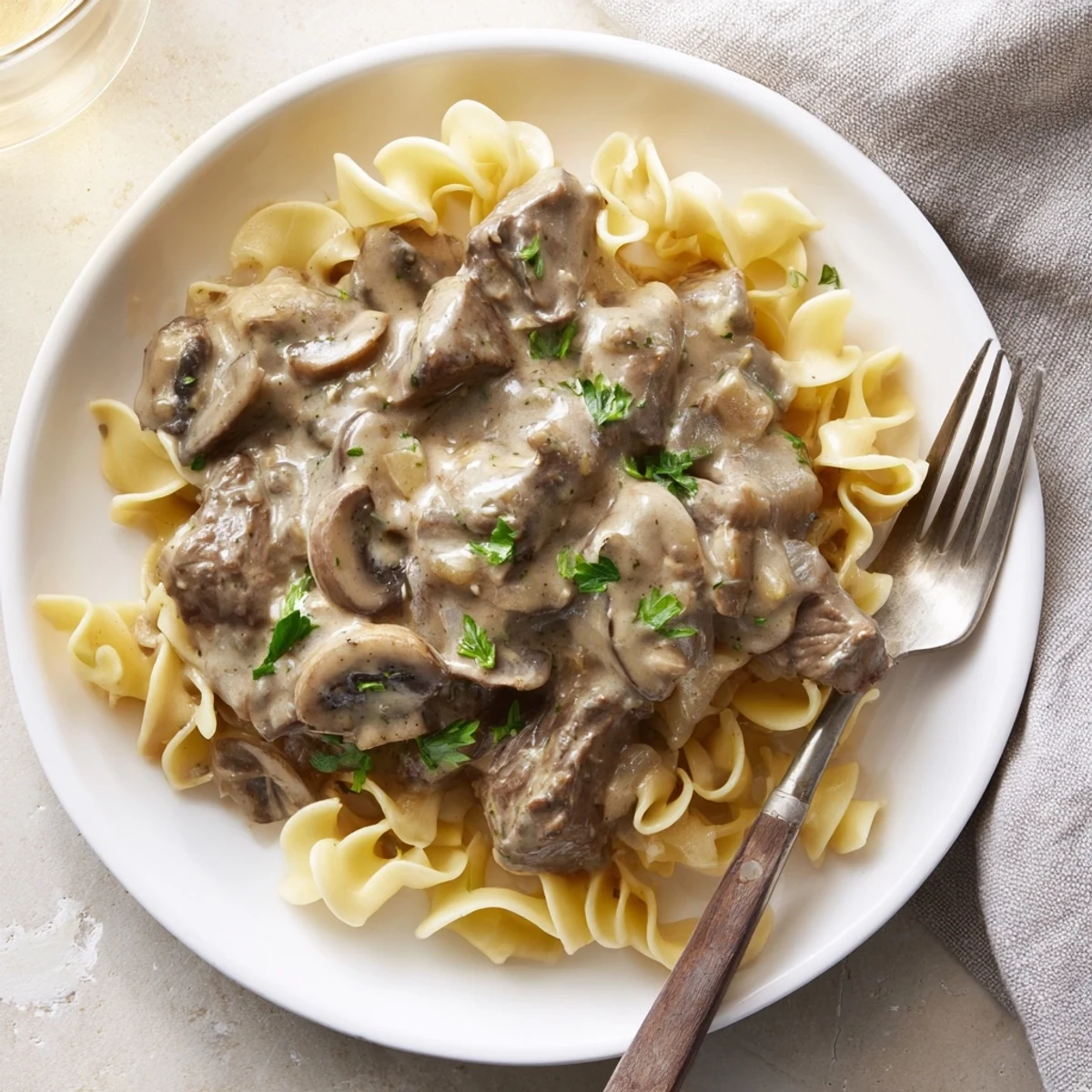 Comforting beef stroganoff served over noodles with tender beef slices and velvety white mushroom sauce