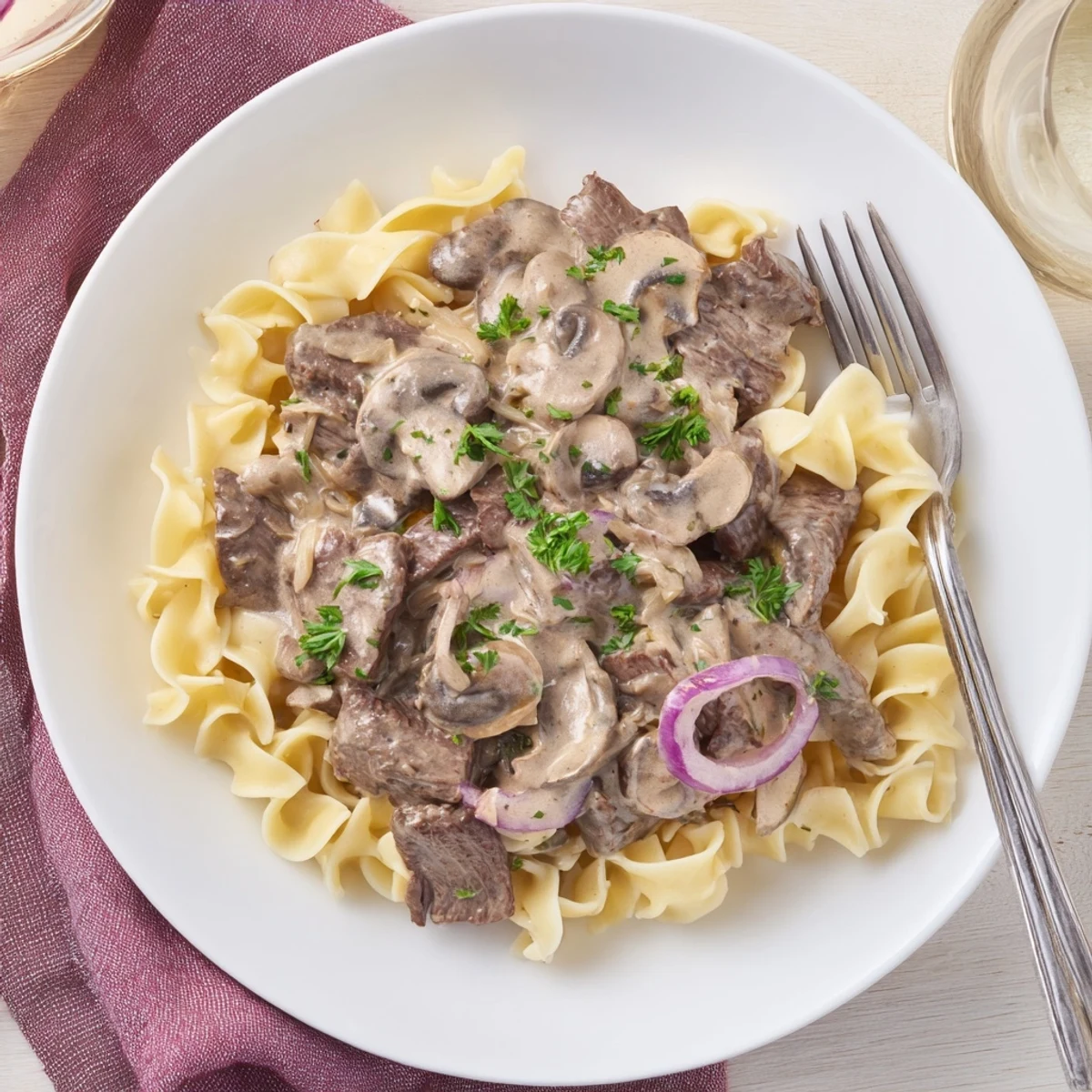 Homemade beef stroganoff featuring seared beef and mushrooms in rich sour cream sauce garnished with parsley