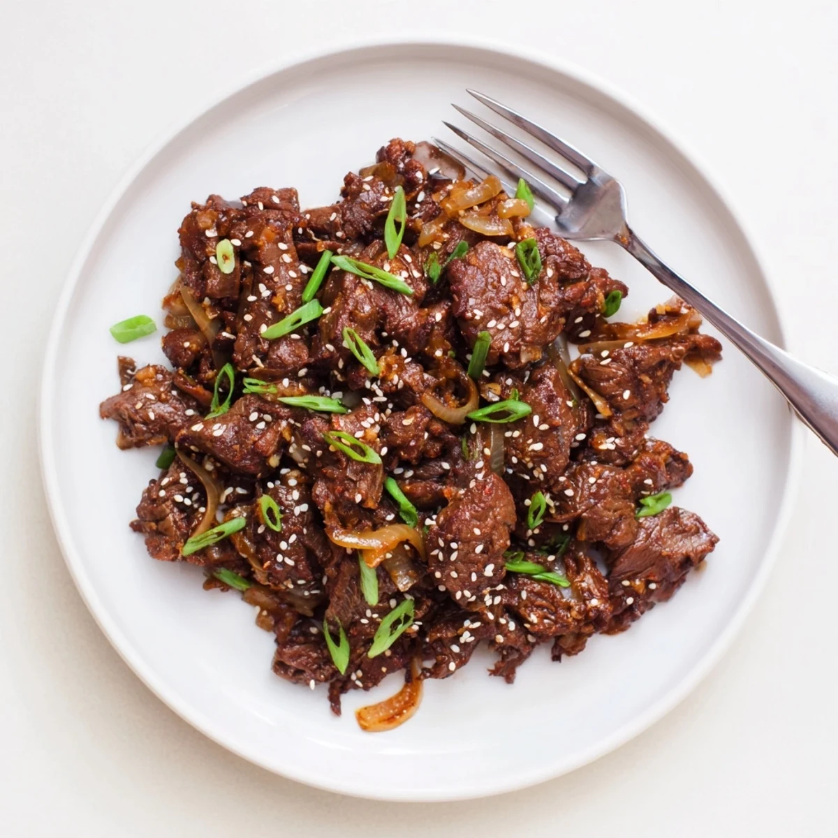 Tender shredded beef in savory Korean sauce with sesame seeds and fresh onions