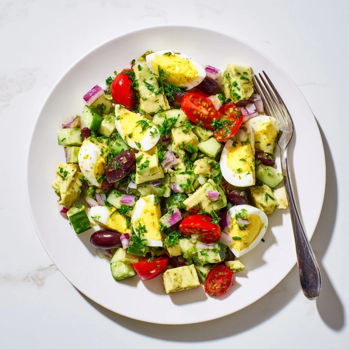 Creamy Mediterranean avocado egg salad served in a white bowl with fresh herbs and cherry tomatoes