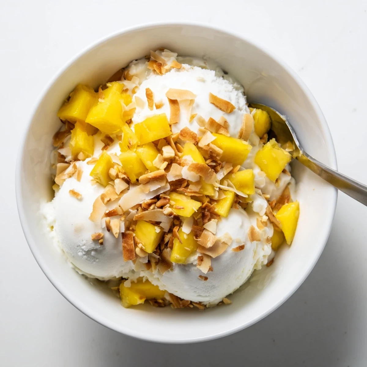Creamy white Thai coconut milk ice cream scooped into a serving bowl with toasted coconut flakes garnish