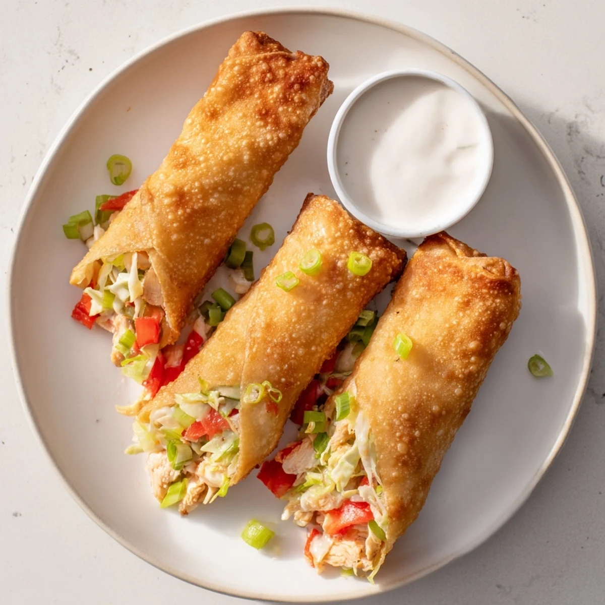 Plate of Voodoo Egg rolls served alongside creamy zesty dipping sauce for a spicy appetizer spread