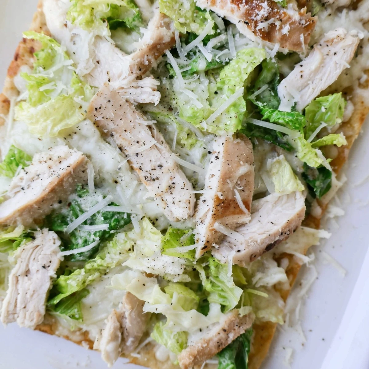 Savory chicken Caesar flatbread loaded with grilled meat, creamy dressing, and fresh vegetables