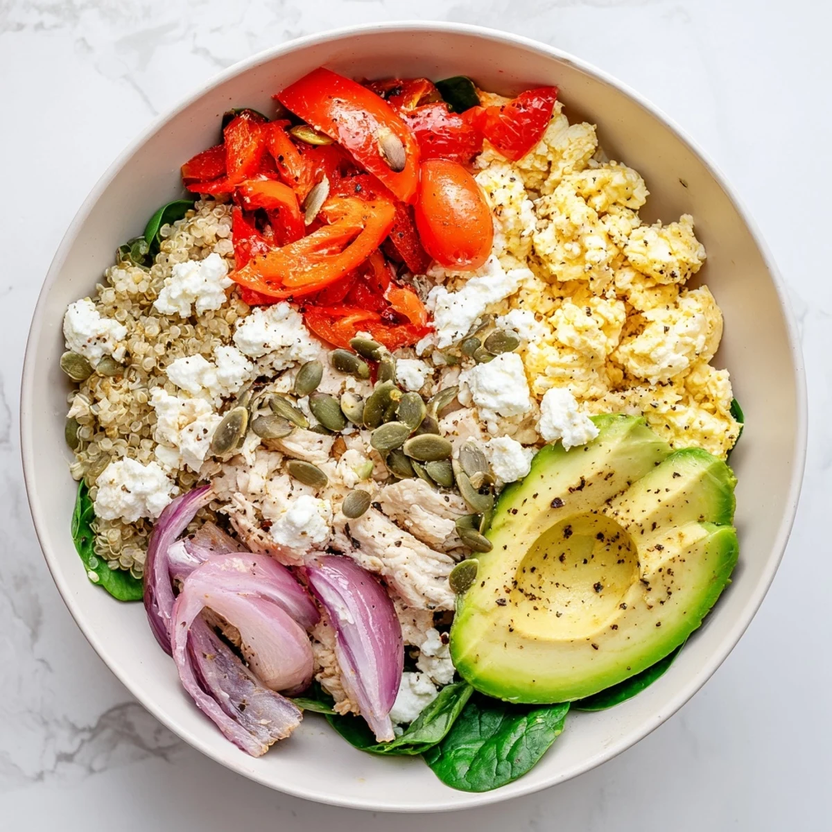 Customizable easy high protein breakfast bowl featuring quinoa, scrambled eggs, spinach, and crumbled feta cheese