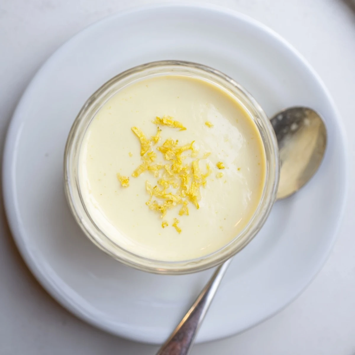 Creamy lemon posset dessert set in clear glass with fresh lemon zest garnish