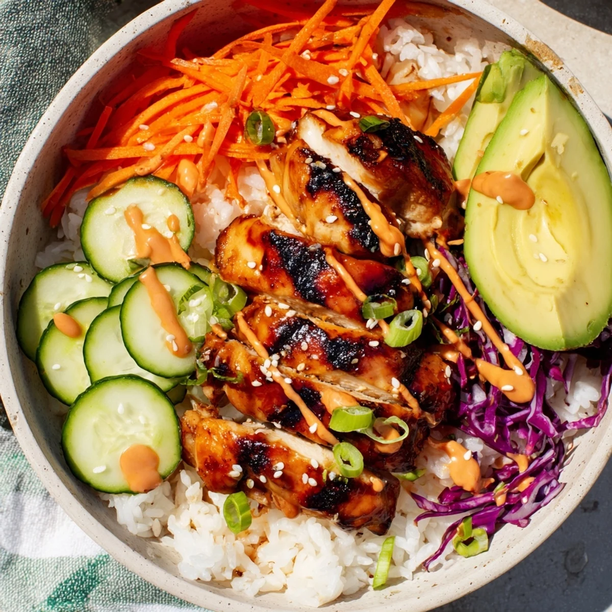 Savory Korean BBQ chicken bowl with charred sliced chicken thigh, crunchy purple cabbage, carrots, cucumber and creamy spicy sauce