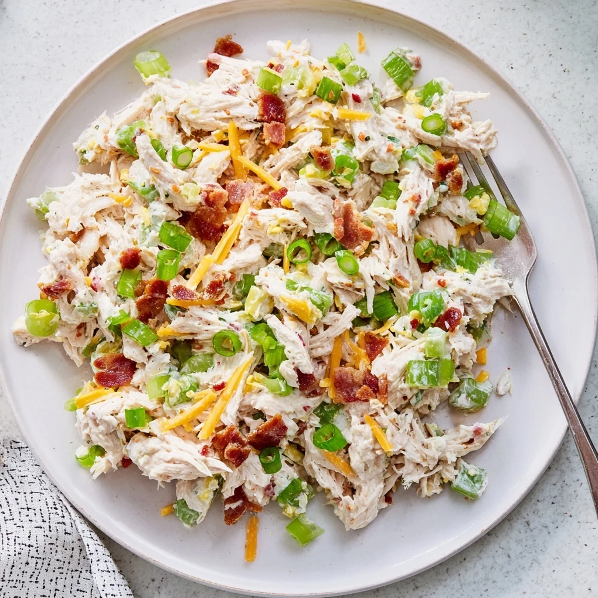 Spoonful of low-carb jalapeno popper chicken salad served in a white bowl with diced jalapenos