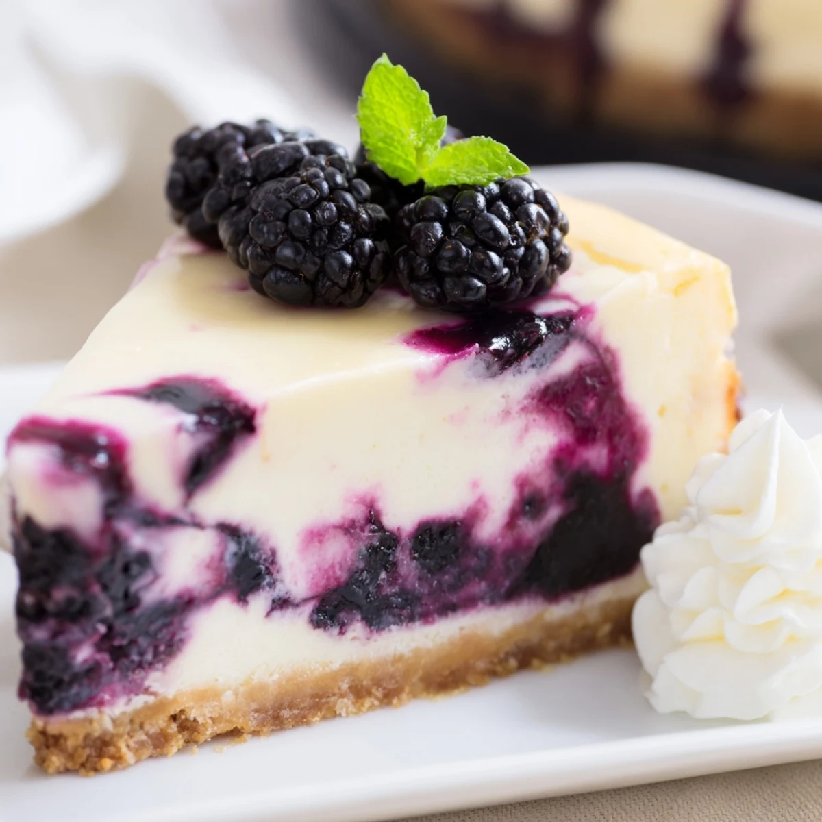 Creamy Blackberry Bliss Cheesecake with purple swirls and fresh berry garnish on white plate