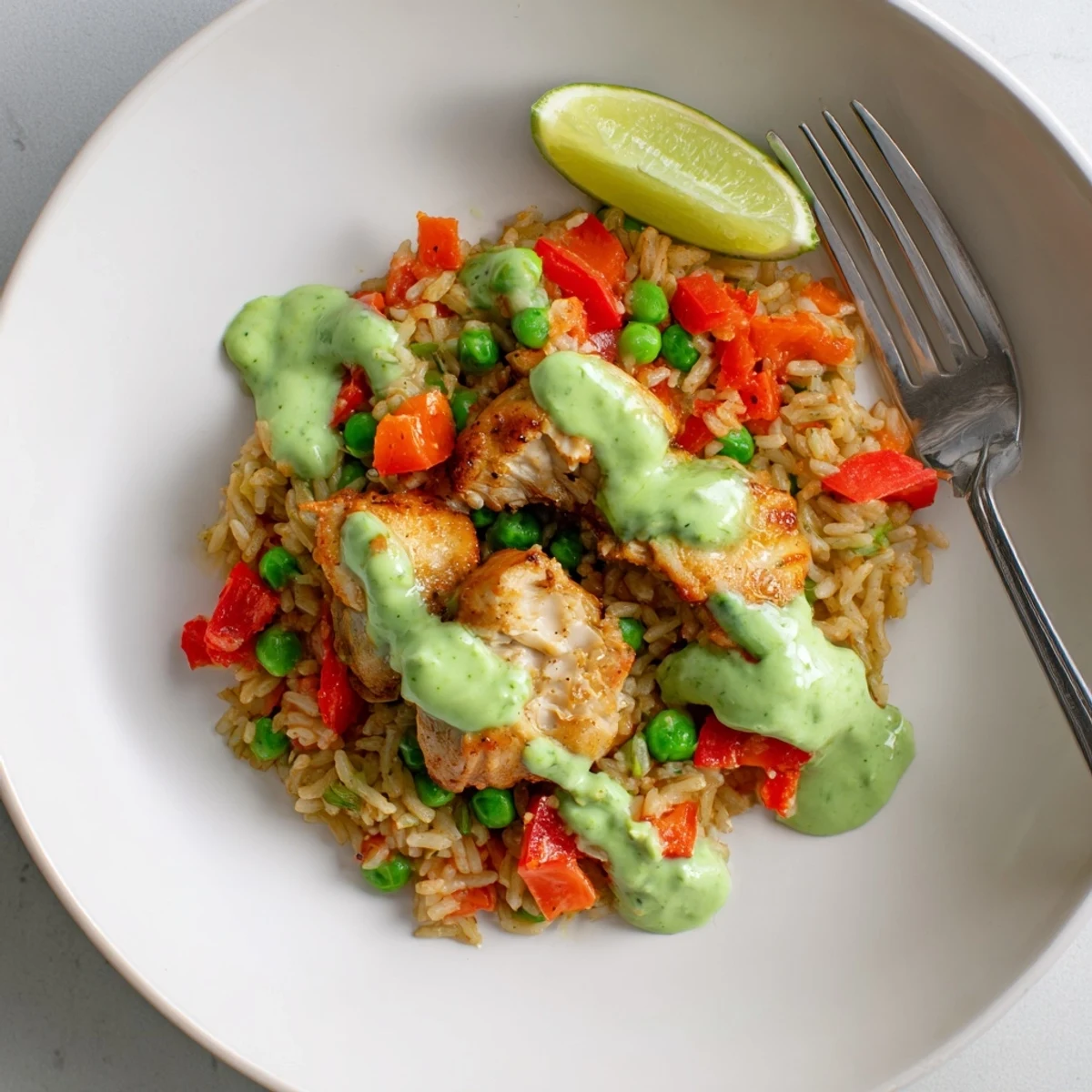 Steaming bowl of Peruvian chicken rice topped with zesty green cilantro sauce and fresh lime wedges