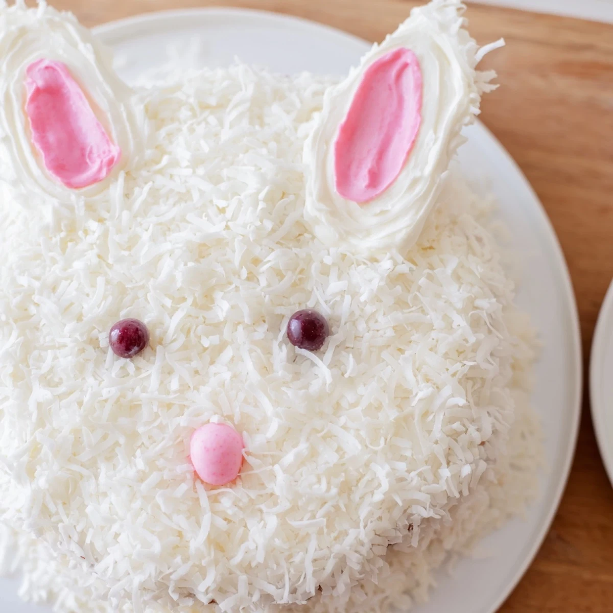 Adorable bunny cake covered in fluffy coconut frosting with candy facial features for Easter