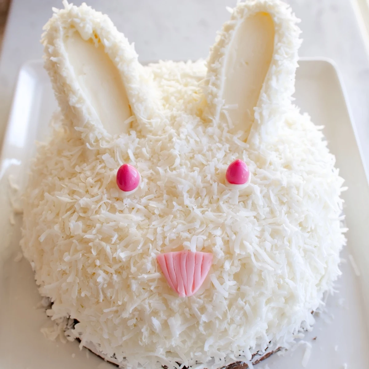 Festive Easter bunny cake shaped with round vanilla layers and buttercream coconut fur coating