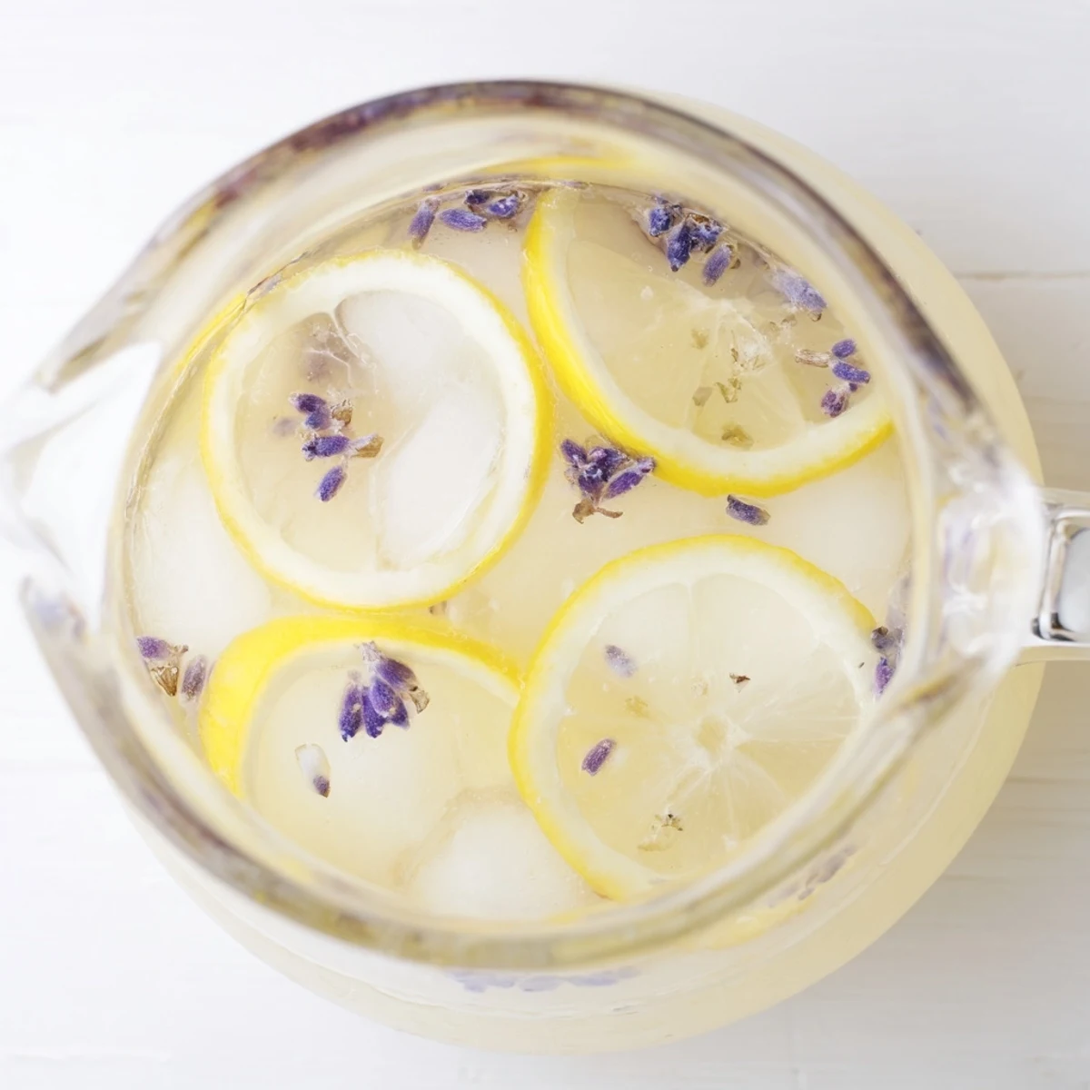 Garnished glass of lavender lemonade on a wooden table with fresh lemon slices