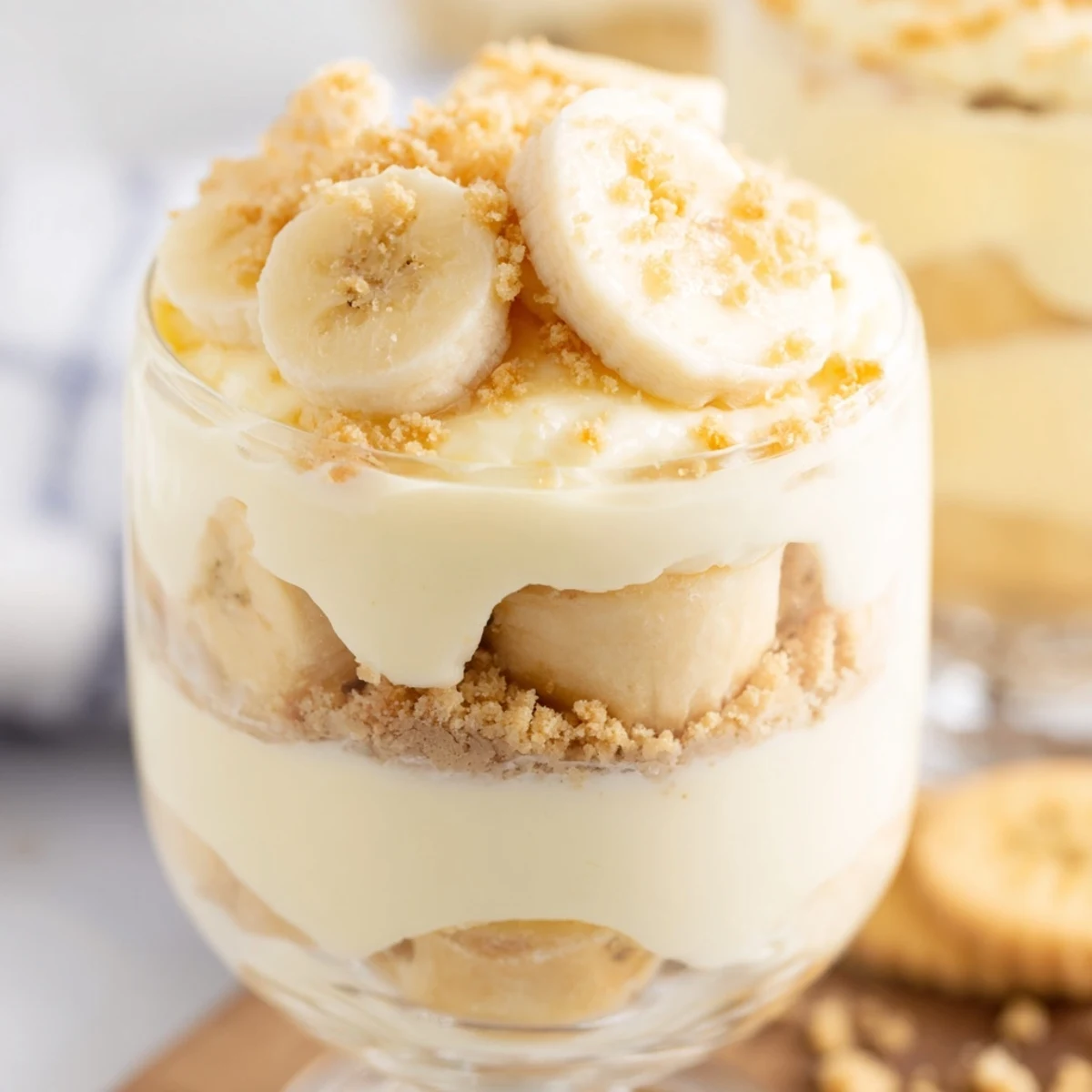 Creamy no bake banana pudding cheesecake cups topped with fresh banana slices and vanilla wafer crumbs